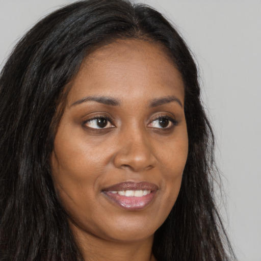 Joyful black young-adult female with long  brown hair and brown eyes