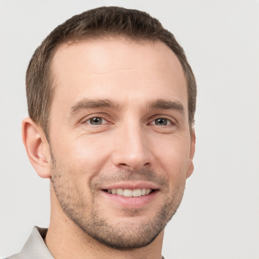 Joyful white young-adult male with short  brown hair and grey eyes