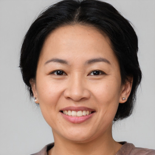 Joyful asian young-adult female with medium  brown hair and brown eyes