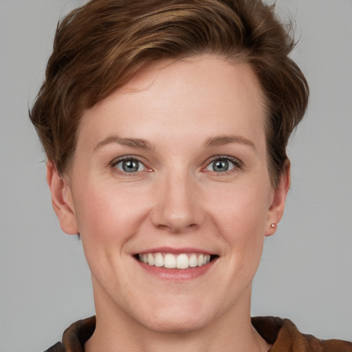 Joyful white young-adult female with short  brown hair and blue eyes