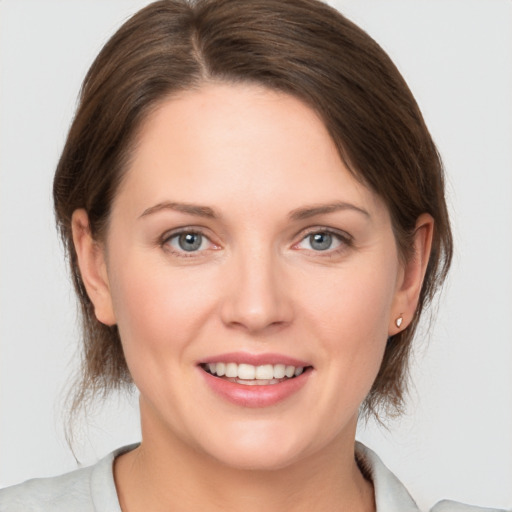 Joyful white young-adult female with medium  brown hair and grey eyes