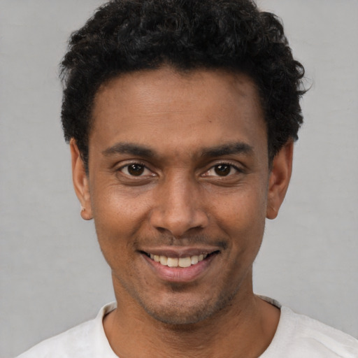 Joyful black young-adult male with short  black hair and brown eyes