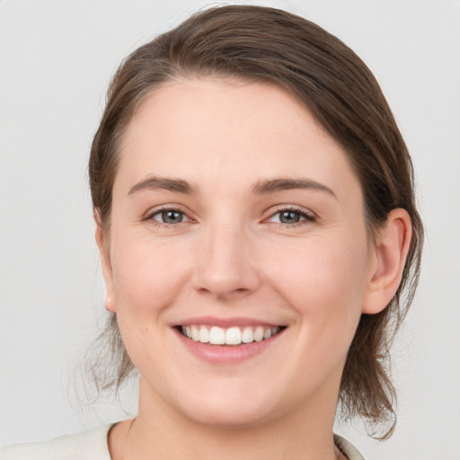 Joyful white young-adult female with medium  brown hair and grey eyes