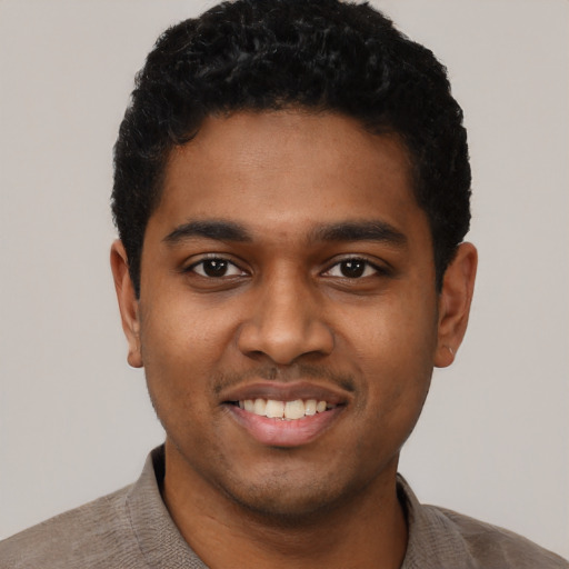 Joyful black young-adult male with short  black hair and brown eyes
