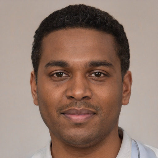 Joyful black young-adult male with short  black hair and brown eyes