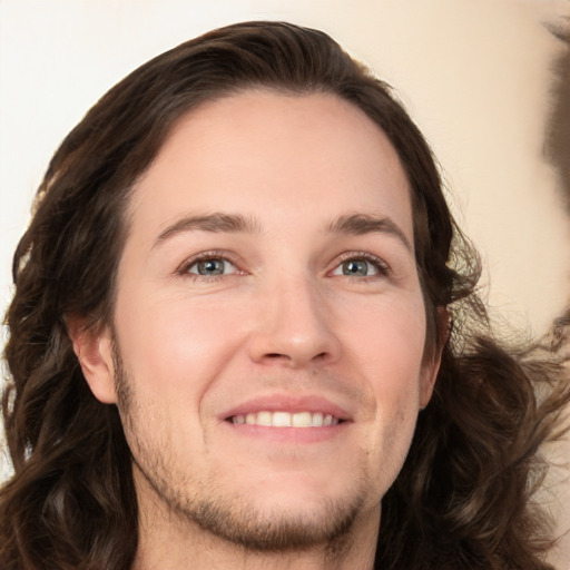 Joyful white young-adult male with long  brown hair and brown eyes