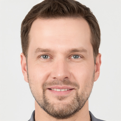 Joyful white young-adult male with short  brown hair and grey eyes