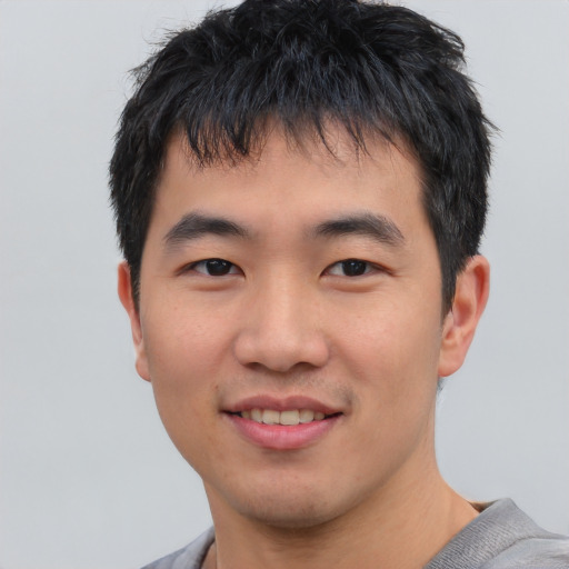 Joyful asian young-adult male with short  black hair and brown eyes