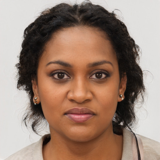Joyful black young-adult female with long  brown hair and brown eyes