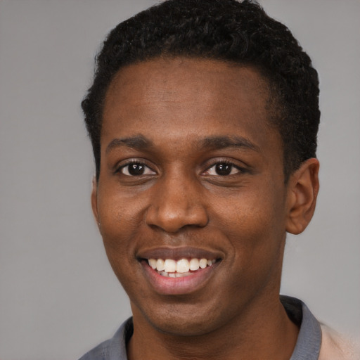 Joyful black young-adult male with short  brown hair and brown eyes