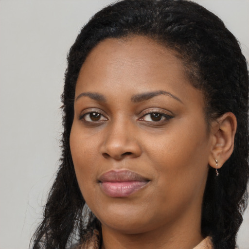 Joyful black young-adult female with long  black hair and brown eyes