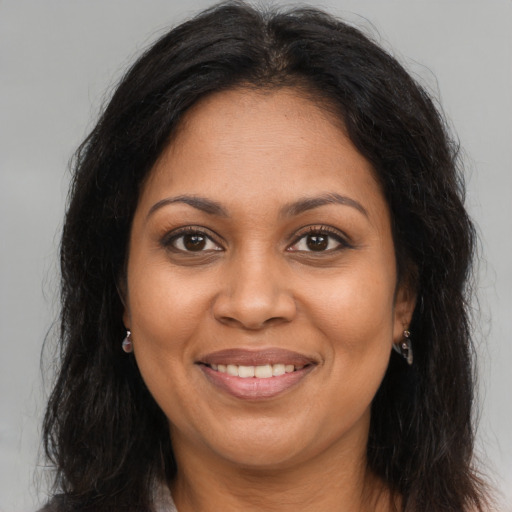 Joyful black adult female with long  brown hair and brown eyes