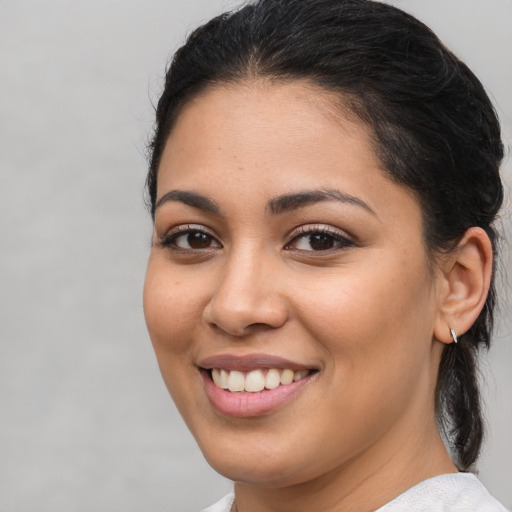 Joyful latino young-adult female with medium  brown hair and brown eyes