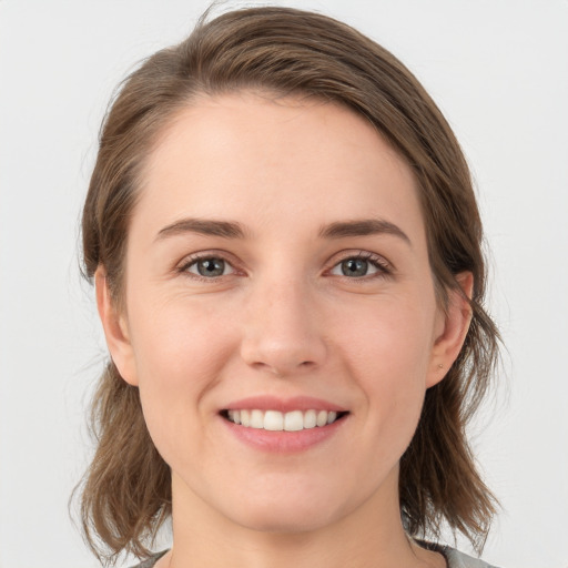 Joyful white young-adult female with medium  brown hair and grey eyes