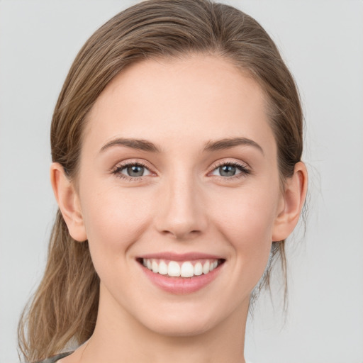 Joyful white young-adult female with medium  brown hair and grey eyes