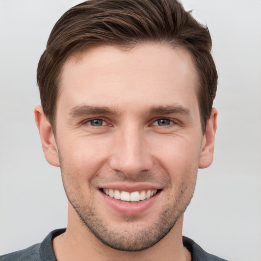 Joyful white young-adult male with short  brown hair and grey eyes