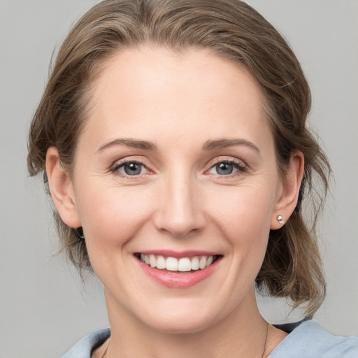 Joyful white young-adult female with medium  brown hair and grey eyes