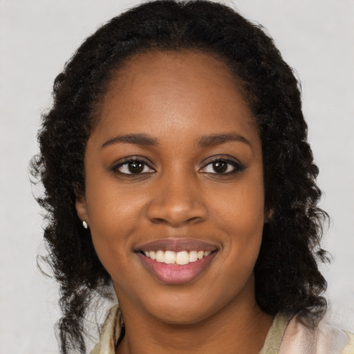 Joyful black young-adult female with long  brown hair and brown eyes