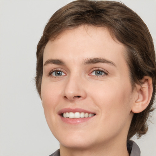 Joyful white young-adult female with medium  brown hair and grey eyes