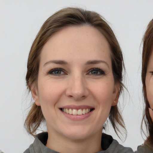 Joyful white young-adult female with medium  brown hair and grey eyes