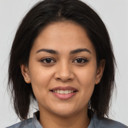 Joyful latino young-adult female with medium  brown hair and brown eyes