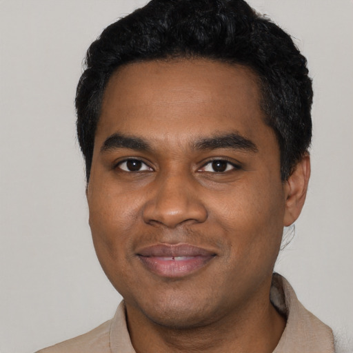 Joyful black young-adult male with short  black hair and brown eyes