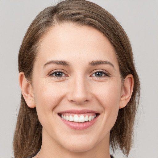 Joyful white young-adult female with medium  brown hair and grey eyes