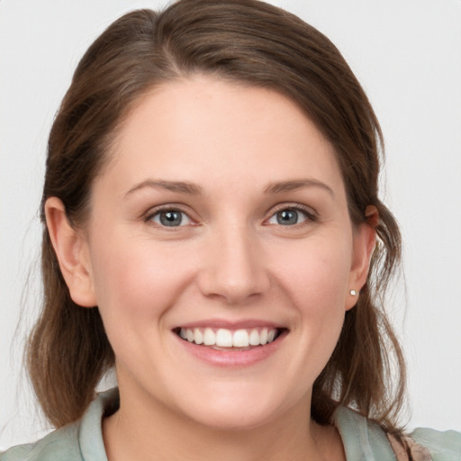 Joyful white young-adult female with medium  brown hair and grey eyes