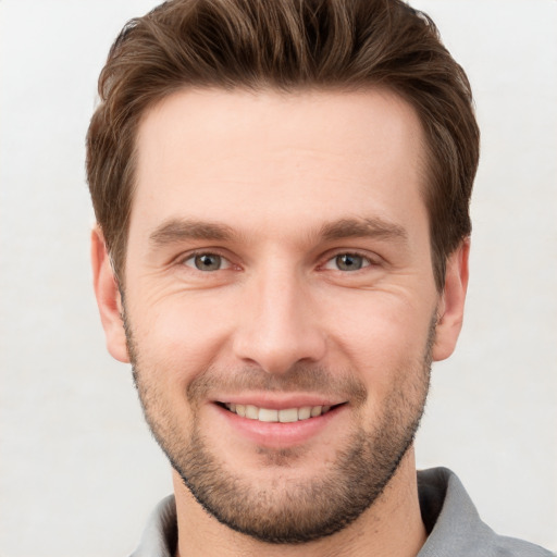 Joyful white young-adult male with short  brown hair and grey eyes