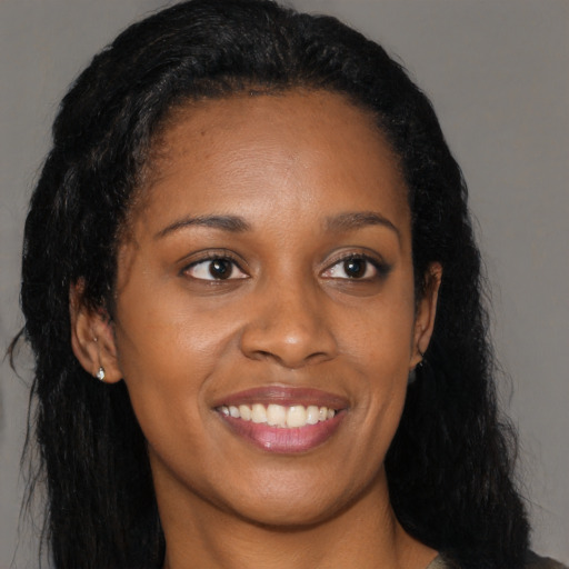 Joyful black young-adult female with long  brown hair and brown eyes