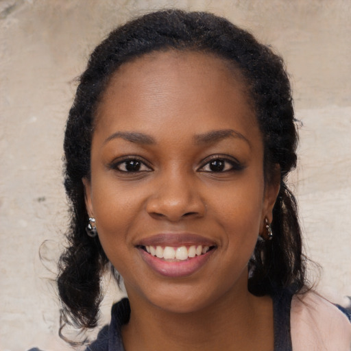 Joyful black young-adult female with long  black hair and brown eyes