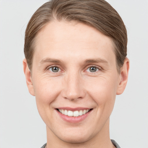 Joyful white young-adult female with short  brown hair and grey eyes