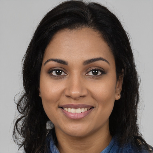Joyful black young-adult female with long  brown hair and brown eyes