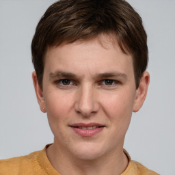 Joyful white young-adult male with short  brown hair and grey eyes