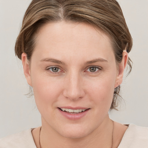 Joyful white young-adult female with medium  brown hair and grey eyes