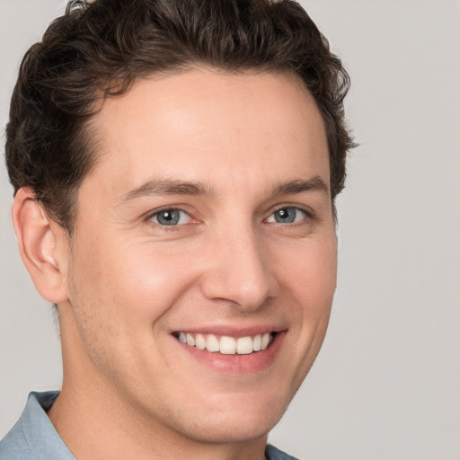 Joyful white young-adult male with short  brown hair and grey eyes