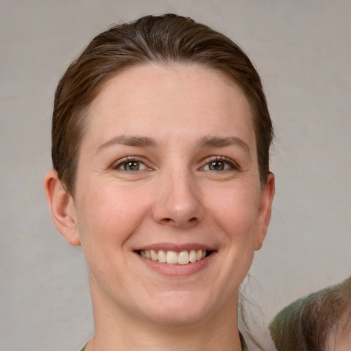 Joyful white young-adult female with short  brown hair and grey eyes