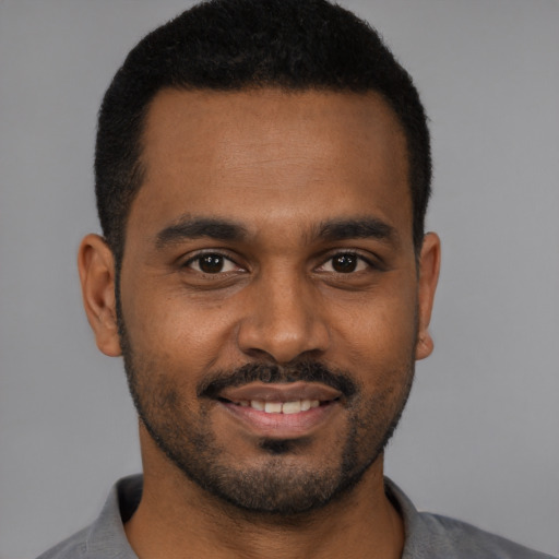 Joyful black young-adult male with short  brown hair and brown eyes