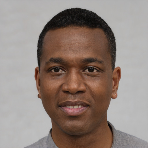 Joyful black young-adult male with short  black hair and brown eyes