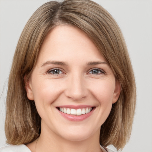 Joyful white young-adult female with medium  brown hair and grey eyes