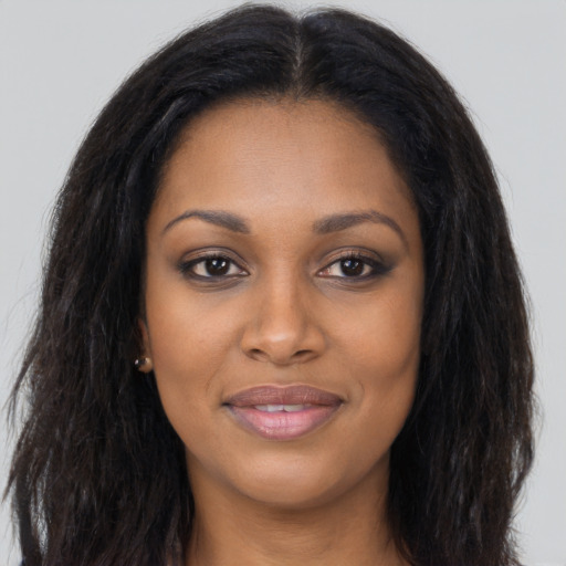 Joyful black young-adult female with long  brown hair and brown eyes