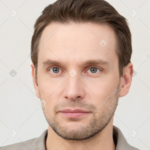 Joyful white young-adult male with short  brown hair and grey eyes