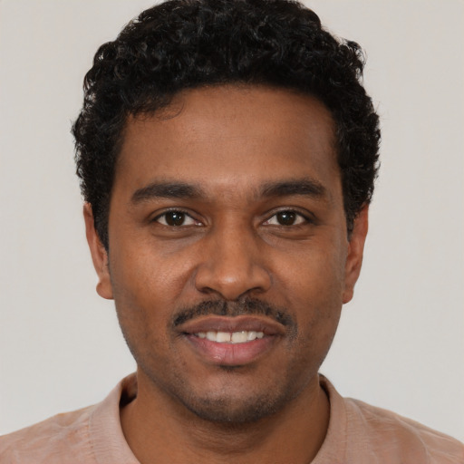 Joyful black young-adult male with short  brown hair and brown eyes