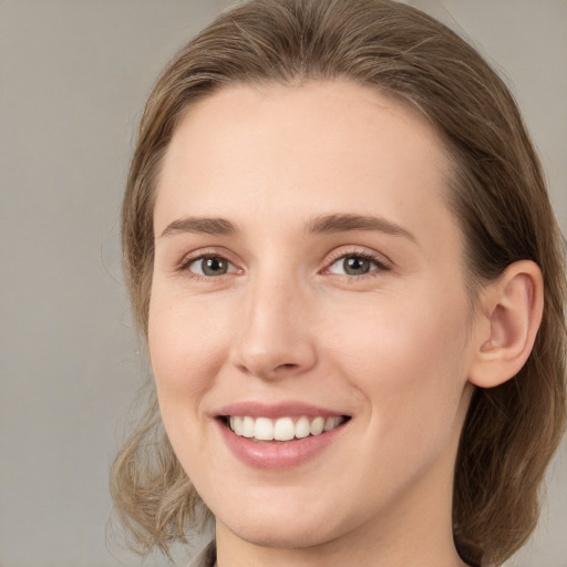 Joyful white young-adult female with medium  brown hair and grey eyes