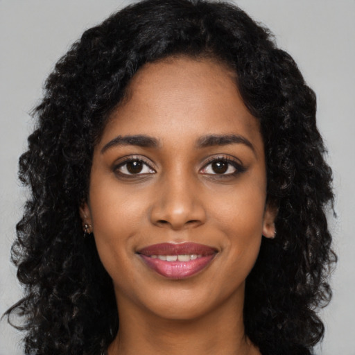 Joyful black young-adult female with long  black hair and brown eyes
