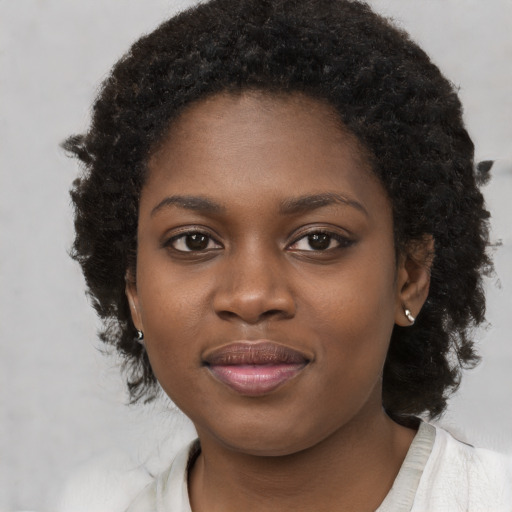 Joyful black young-adult female with long  brown hair and brown eyes