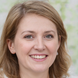 Joyful white adult female with medium  brown hair and green eyes