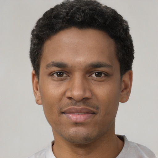 Joyful black young-adult male with short  black hair and brown eyes