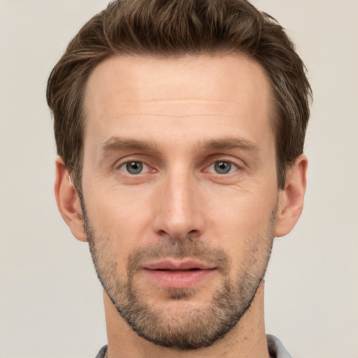 Joyful white young-adult male with short  brown hair and grey eyes