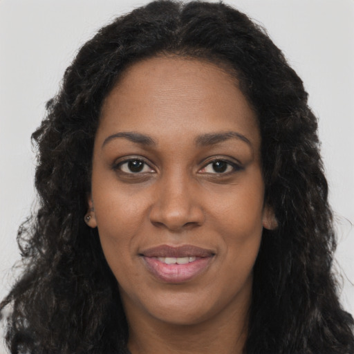 Joyful black young-adult female with long  black hair and brown eyes